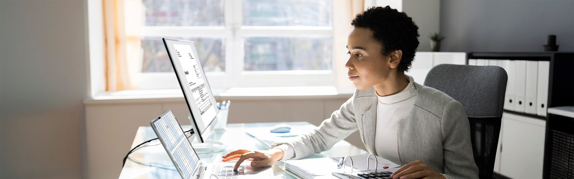 The image shows a modern office setting with a desk that has a laptop and additional screens, indicating a work environment that might involve data analysis or digital tasks.